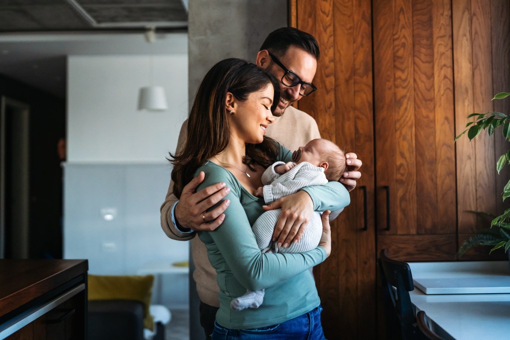 Parents holding newborn symbolizing the value of life insurance for kids.